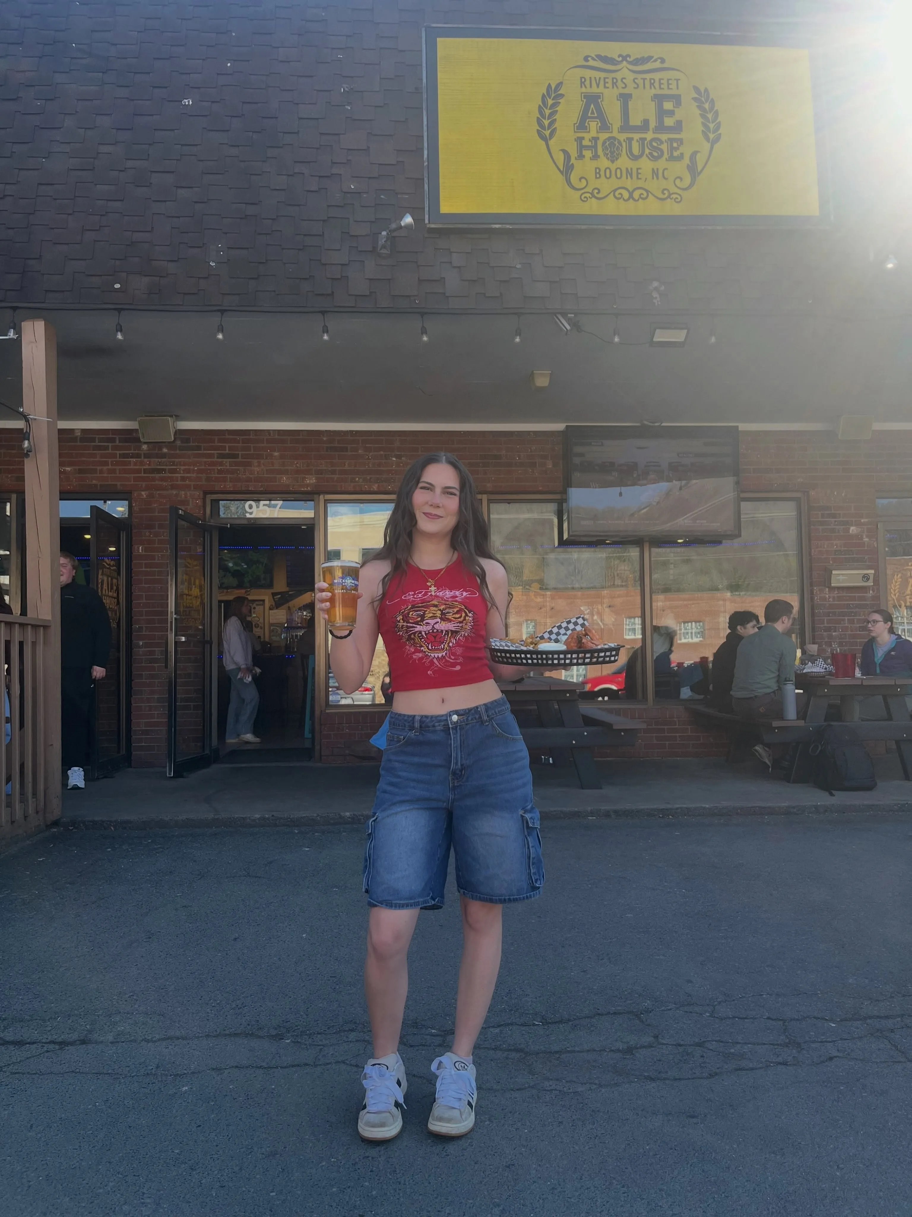 Server holding a beer and a basket of wings outside Rivers Street Ale House